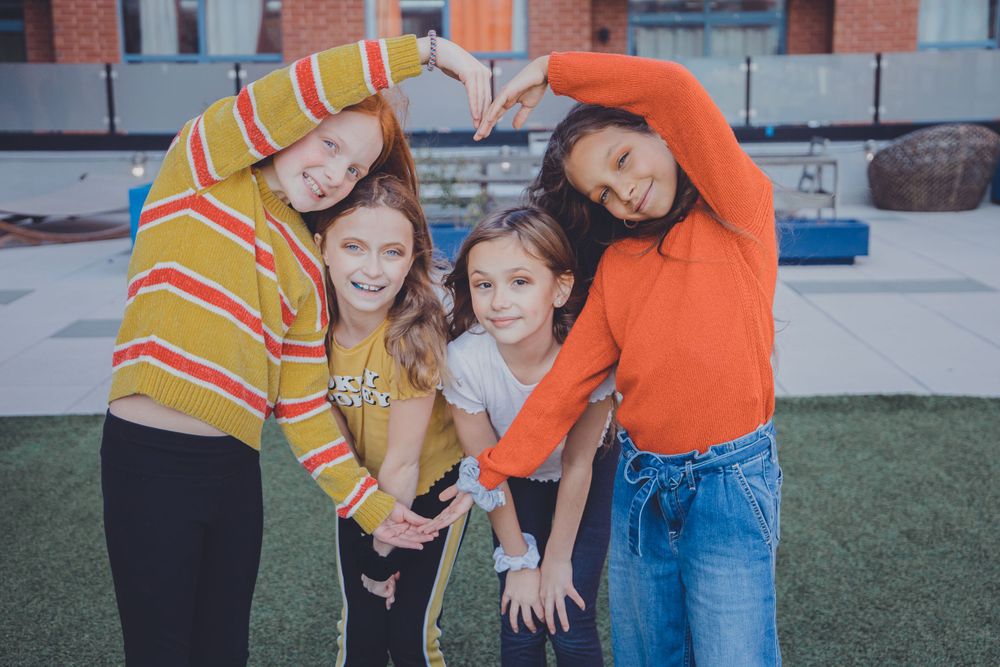 A playful group poses together on grass near a brick building.