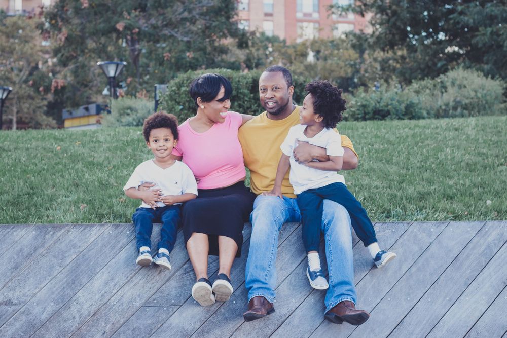 Family relaxing together during outdoor photo session on wooden deck.