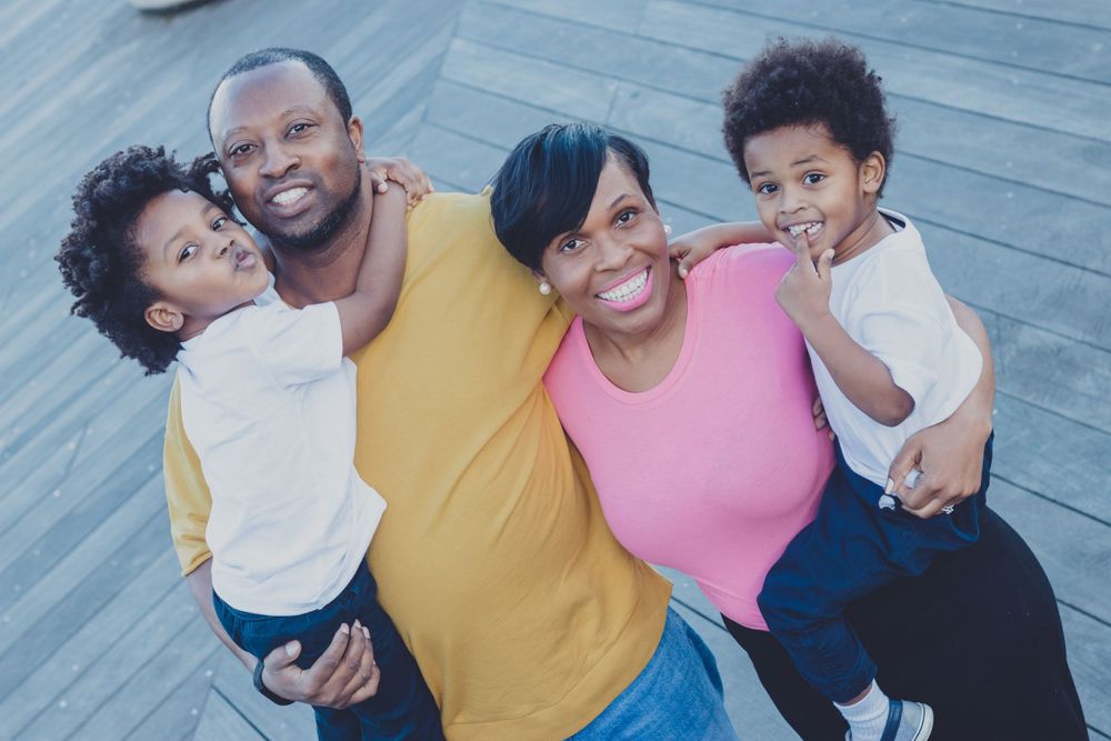 Joyful family embracing and laughing during casual outdoor photoshoot.