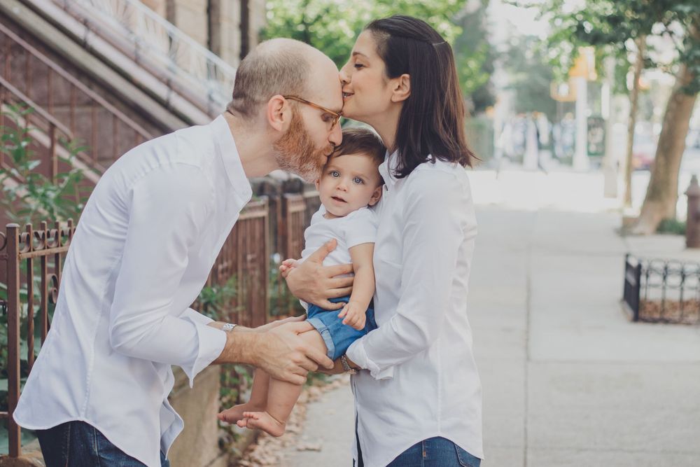 Sweet family interactions during casual photoshoot on city sidewalk.