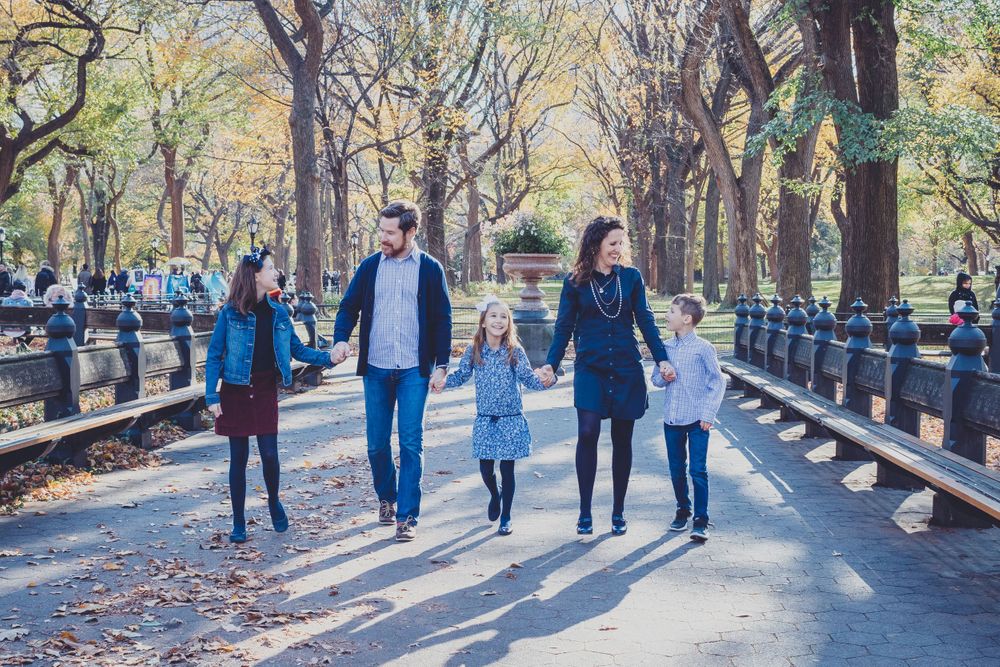 Groups walking along tree-lined pathway during fall season.