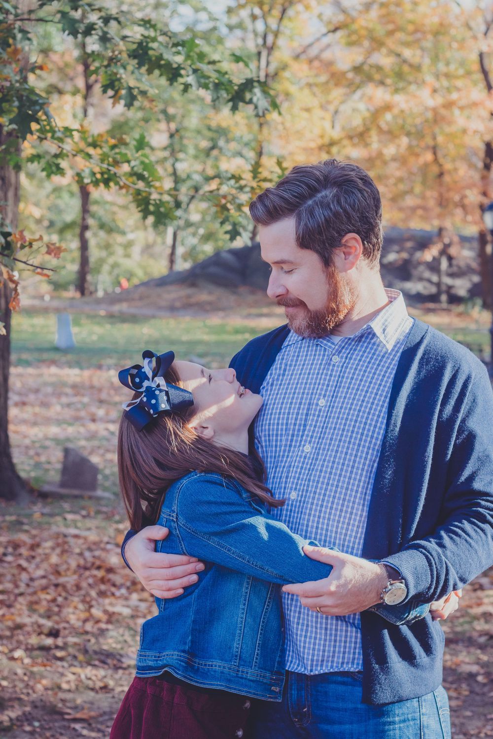 Couple embracing outdoors among fall foliage in casual attire.