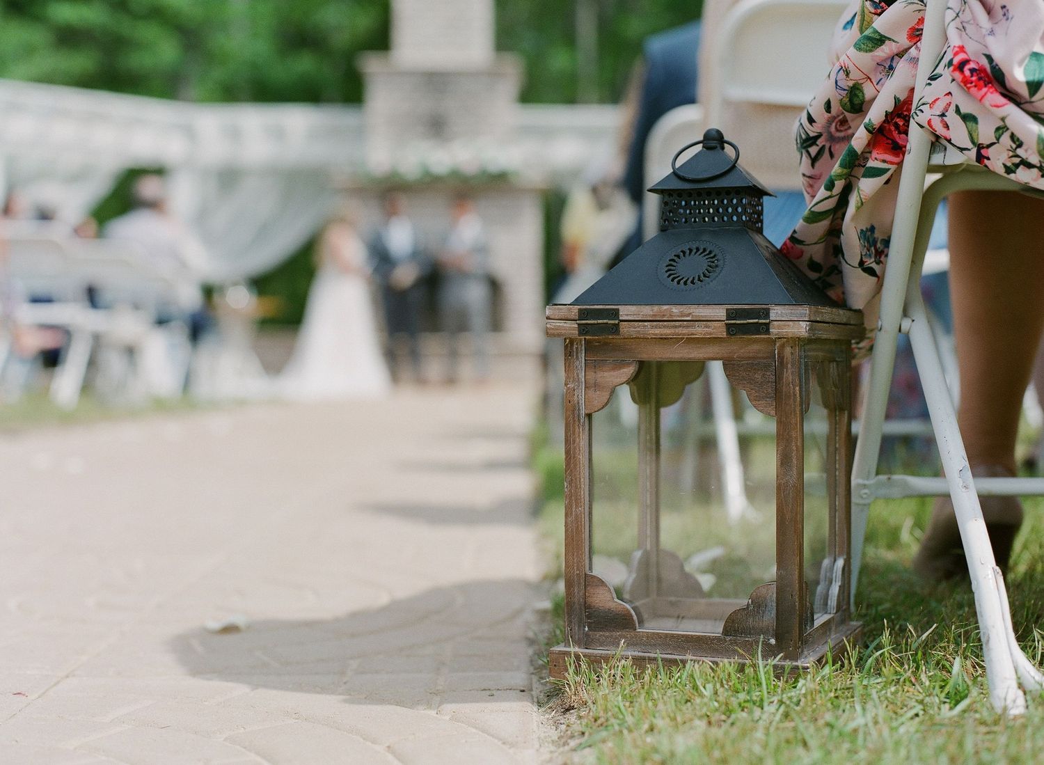 Rustic lantern decoration along outdoor wedding ceremony aisle with chairs in background.