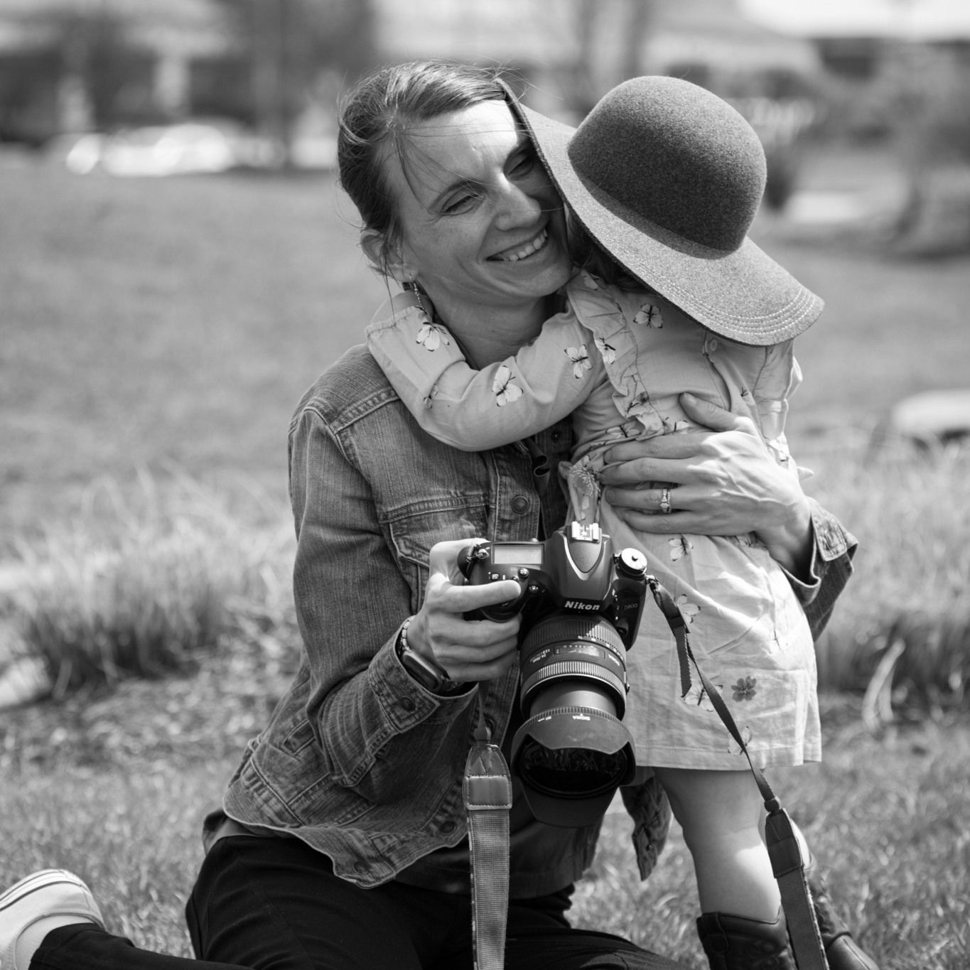 woman with camera and child in hat hugging