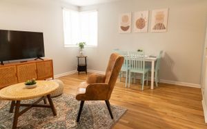 Contemporary living space with mint dining set, brown chair, and minimalist wall art in warm tones.