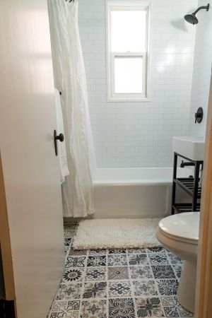 Modern bathroom with white subway tile, patterned floor, and black fixtures.