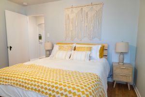 Contemporary bedroom with yellow polka dot bedding and macrame wall hanging above headboard.
