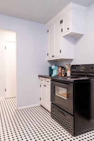 Modern kitchen featuring black appliances, white cabinetry, and geometric floor tiles.