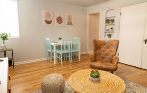 Bright interior space with round woven table, pouf ottoman, and mint green dining furniture.