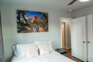 Bedroom featuring mountain landscape canvas art, white bedding, and hardwood floors.