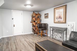 Modern basement lounge area with grey furniture and hardwood-style flooring.