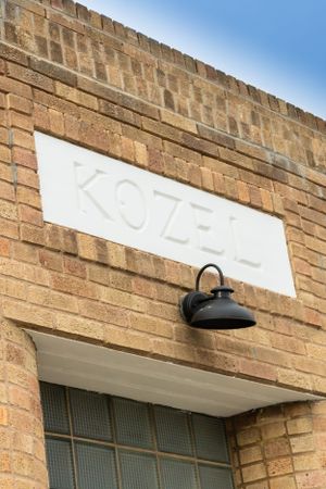 Exterior brick wall with white signage and black light fixtures mounted above.