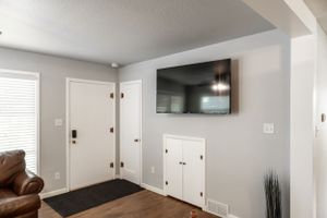 Contemporary living area with mounted TV, white doors, and hardwood flooring.