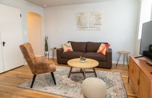 Living room with brown sofa, tan accent chair, and round coffee table on geometric area rug.