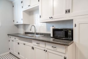 White kitchen with granite countertops, built-in microwave and traditional cabinet hardware.