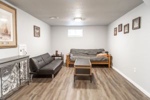 Finished basement living space with grey flooring and wall art.