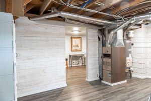 Large open basement area with white walls and wood-look flooring.