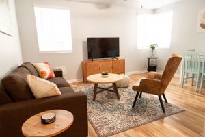 Modern living room with brown sofa, wooden coffee table, and accent chair arranged on patterned area rug.