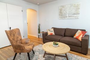 Contemporary living room featuring dark sofa, vintage-style armchair and circular wooden coffee table.