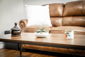 Modern coffee table with succulent plants and decorative items next to brown leather couch.