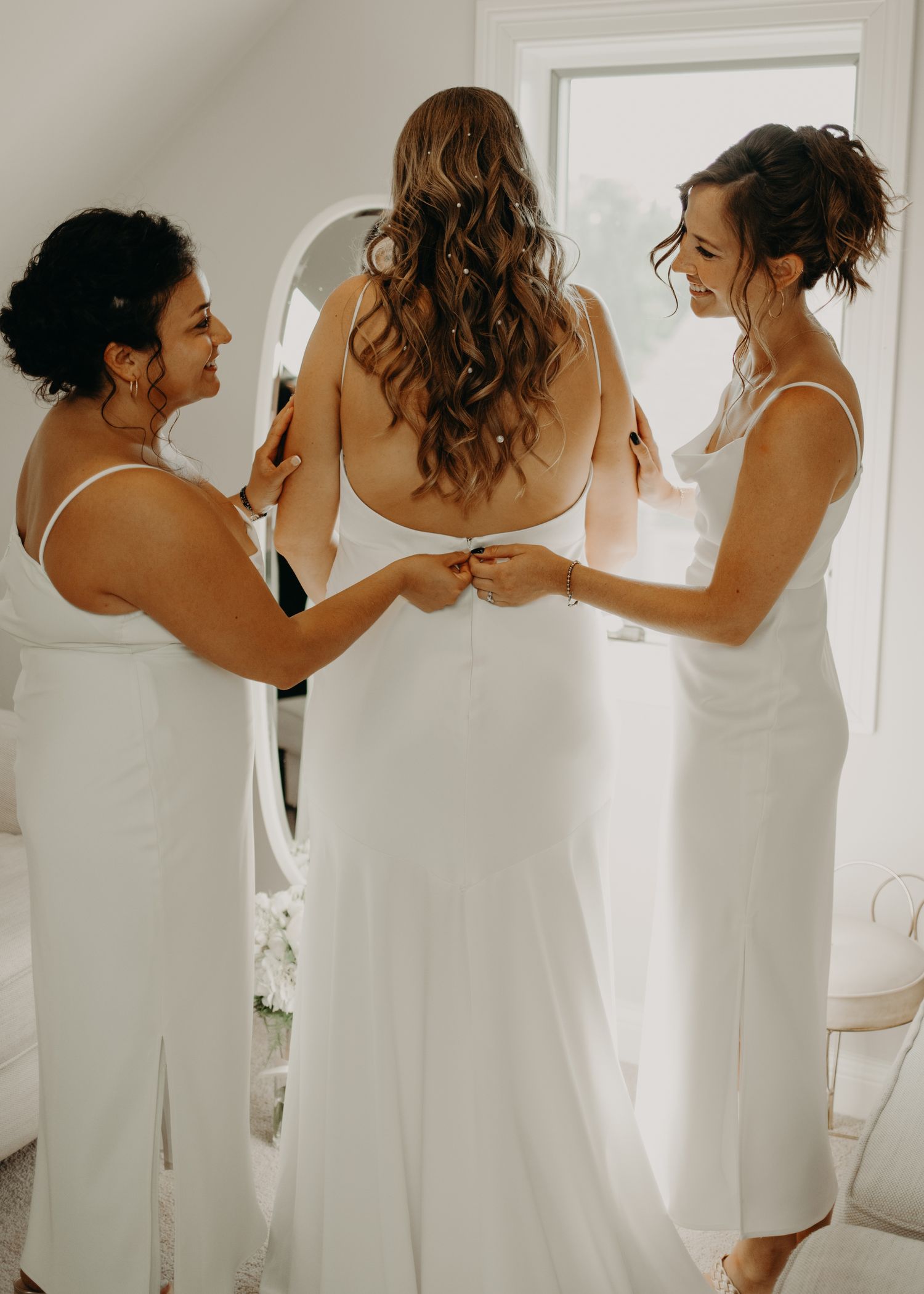 Wedding party helping with the back of an elegant white wedding dress.