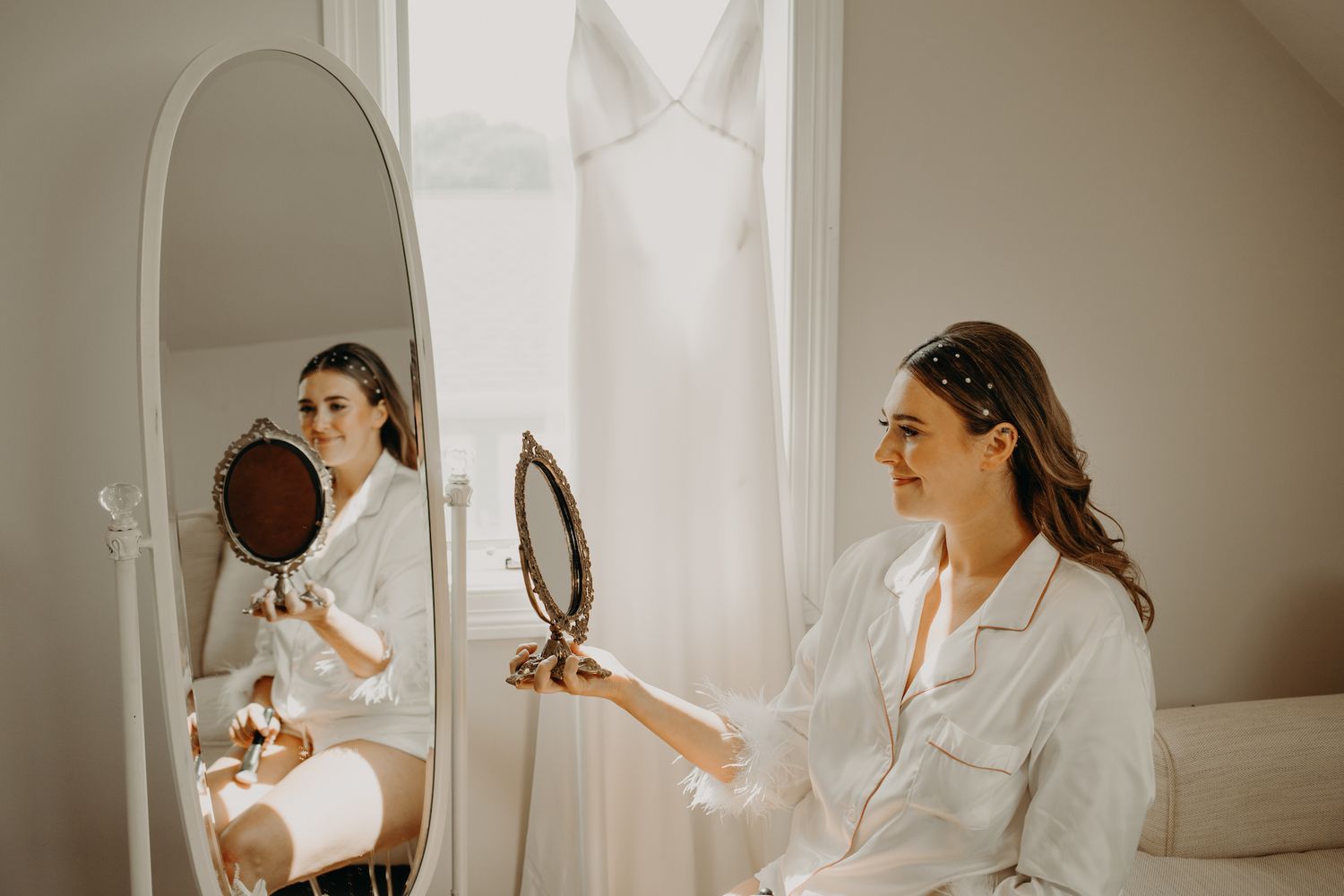 Wedding morning preparation scene with mirror reflection in bright white room.