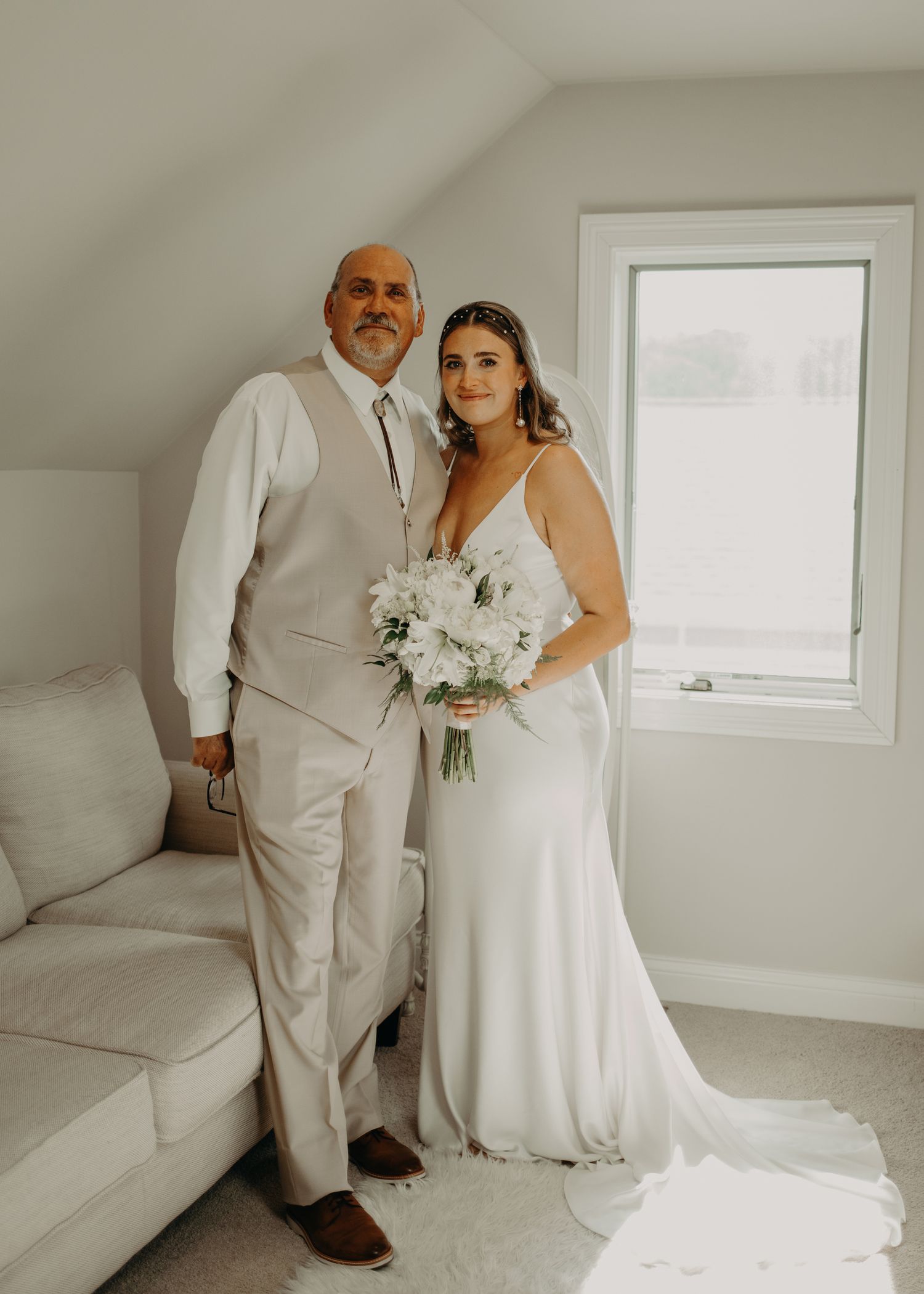 A tender moment between a bride in white dress holding a bouquet and her companion in a light-colored suit.