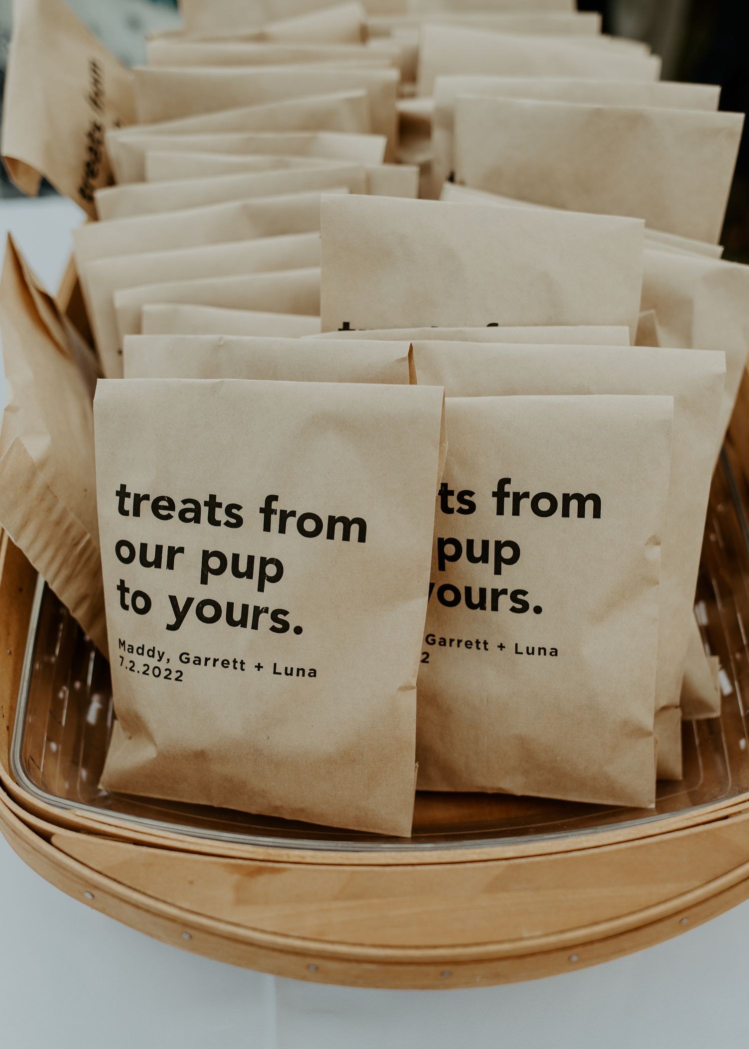 Brown paper bags labeled 'treats from our pup to yours' arranged in a basket.