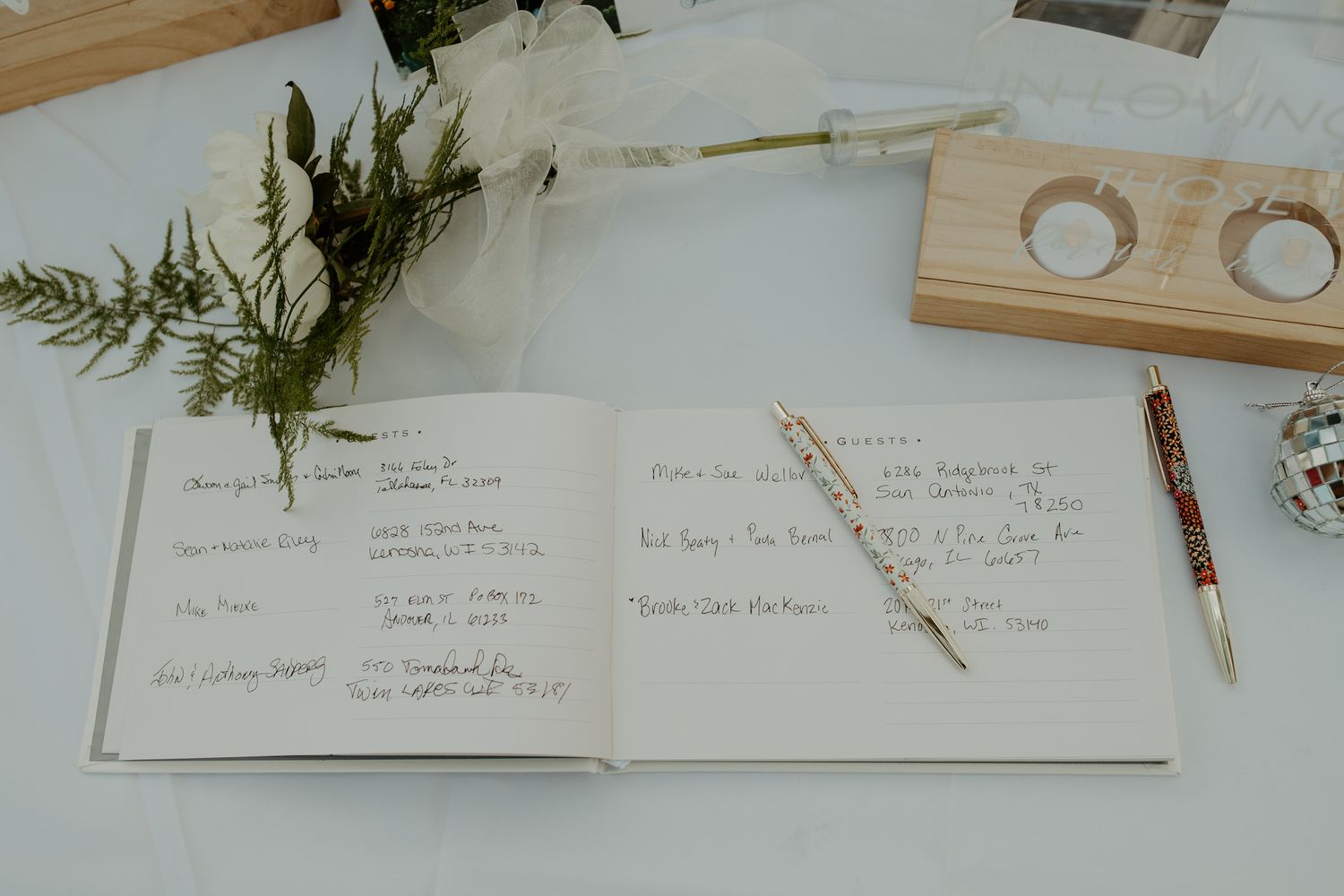 Open guest book with handwritten notes and decorative greenery.