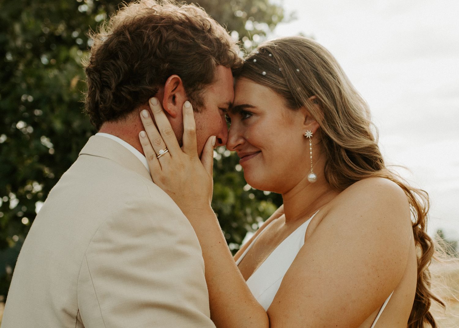 Intimate moment between newlyweds sharing tender touch in outdoor setting.