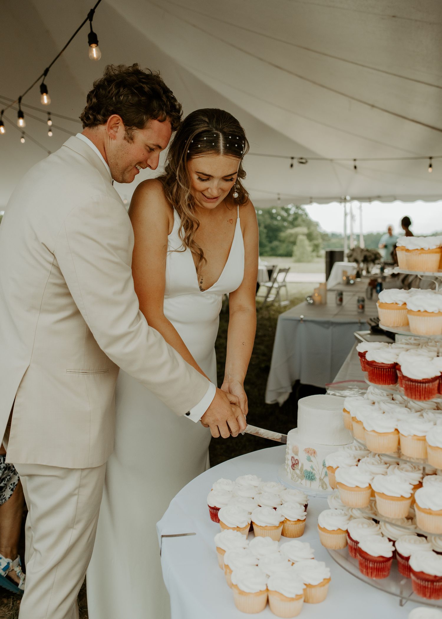 Newlyweds sharing a sweet moment while cutting desserts at their wedding reception.