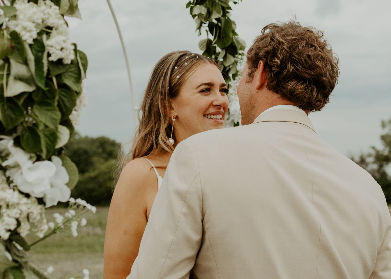 Romantic outdoor wedding moment set against a cloudy sky.