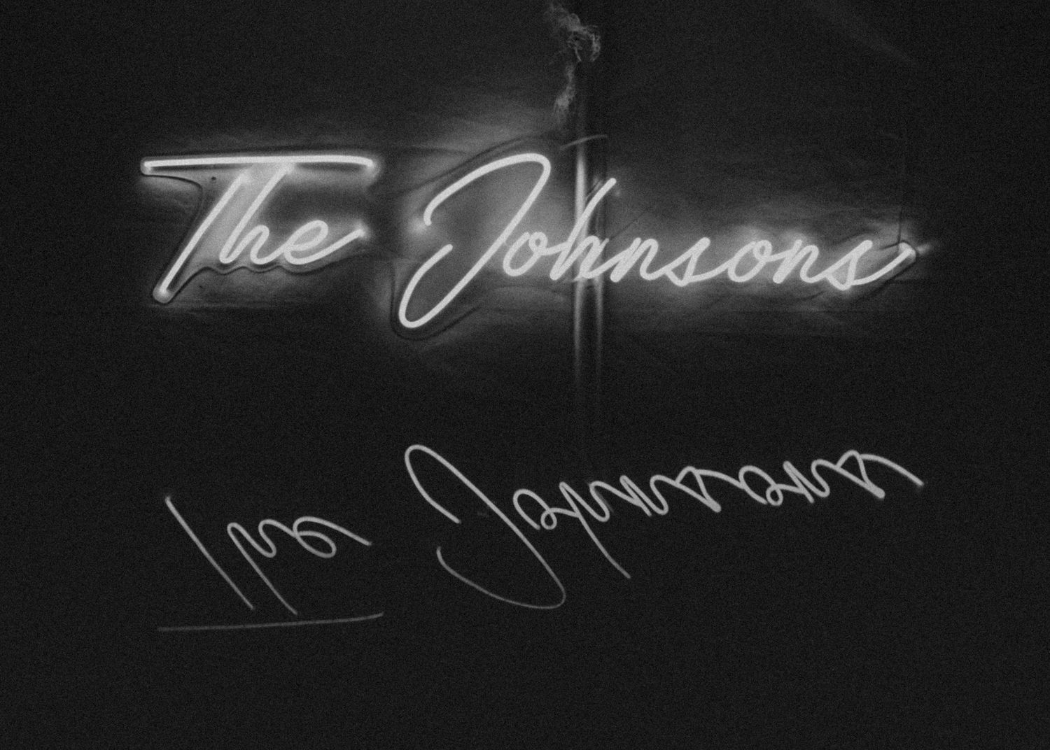 Neon sign displaying cursive text against dark background.