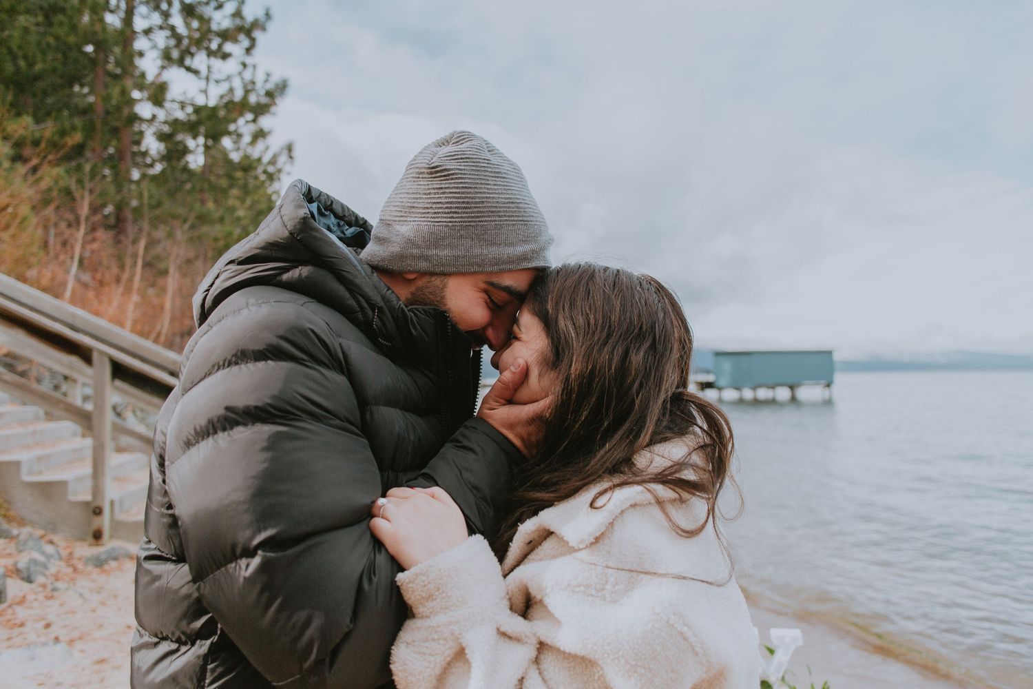 Just engaged couple embracing after surprise proposal on the shore of Lake Tahoe engagement ring Lake Tahoe and mountain
