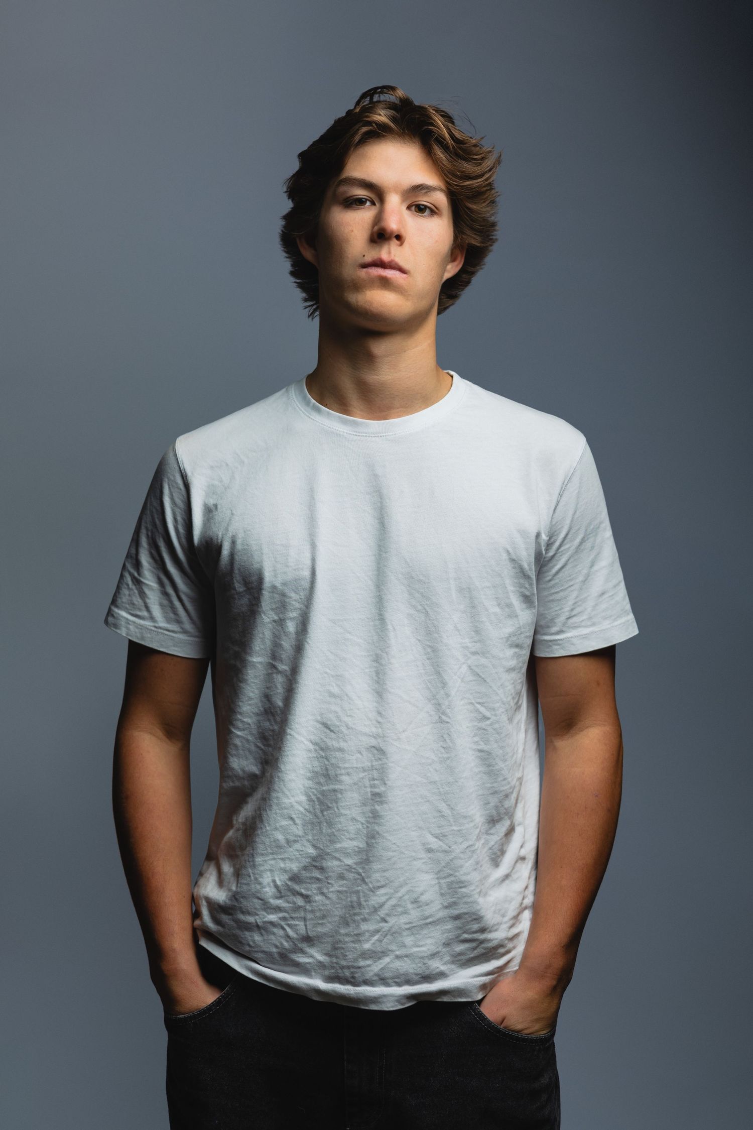 Portrait of person in casual white t-shirt against grey studio background.