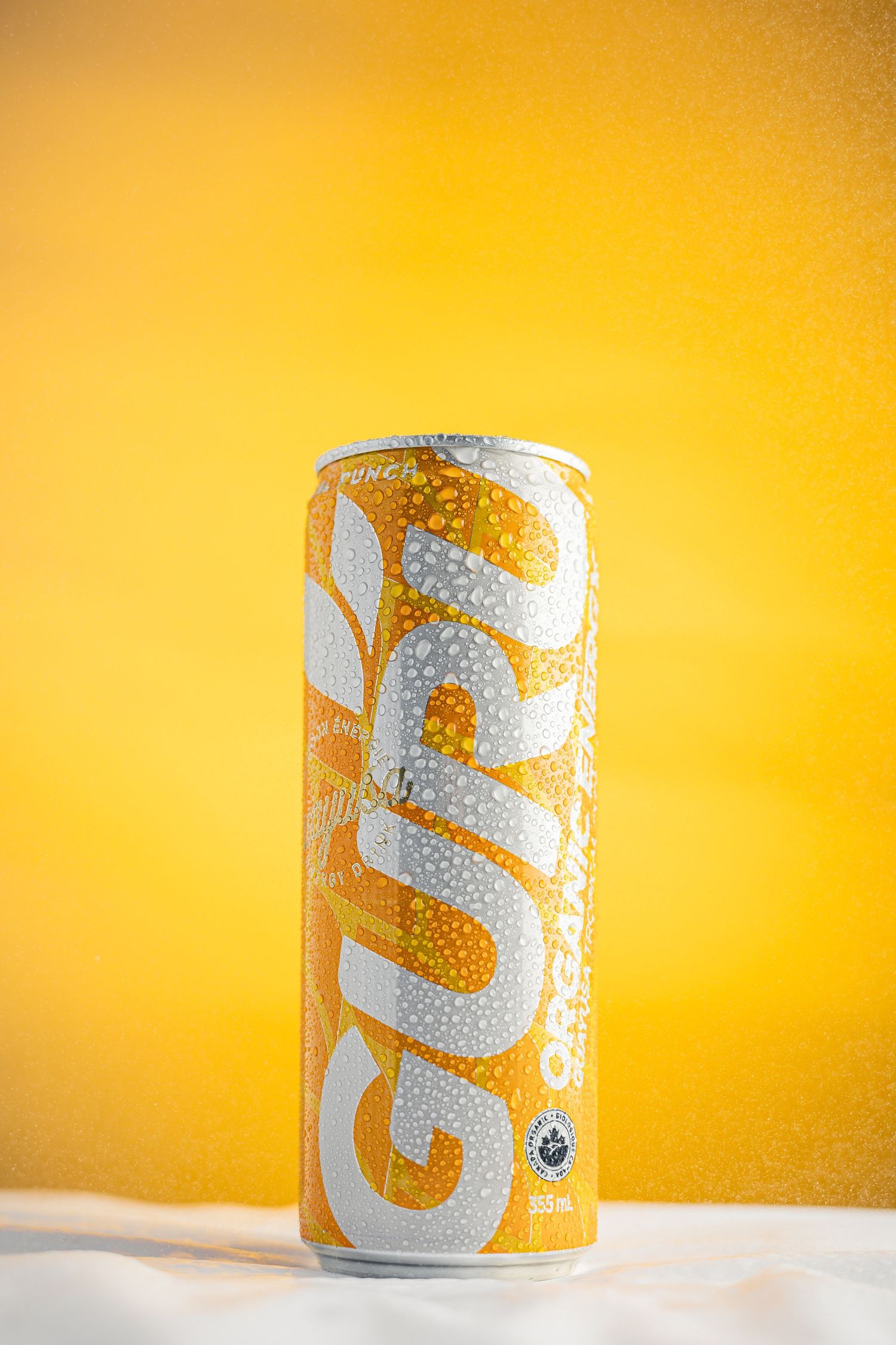 Can of Guru energy drink with condensation against vibrant yellow background.