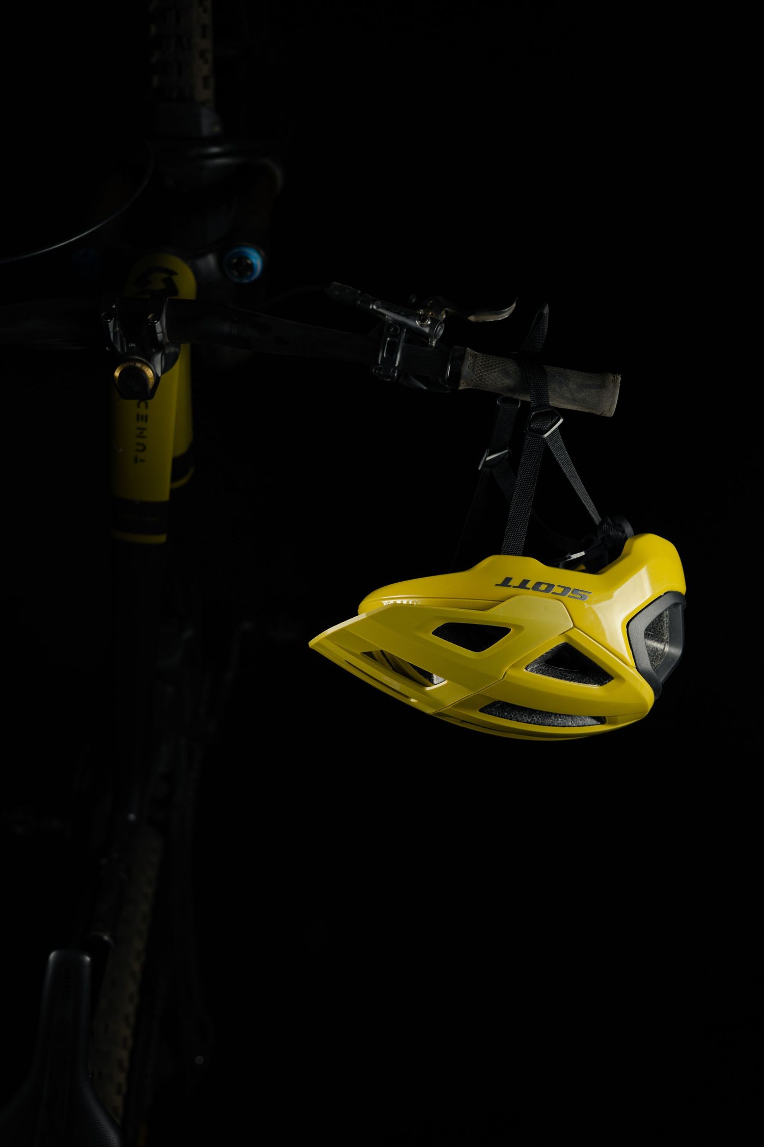 Yellow bicycle helmet photographed in dramatic low-key lighting against black background.