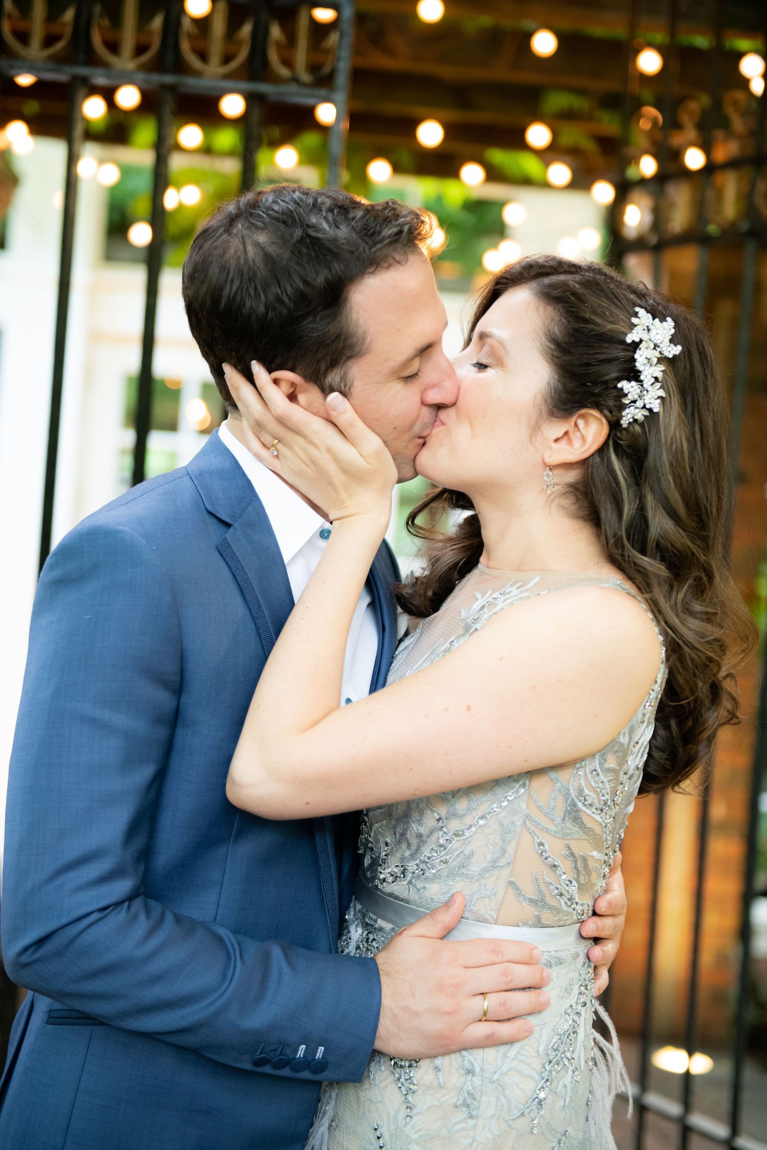 Romantic moment between a couple in formal attire under twinkling outdoor lights.