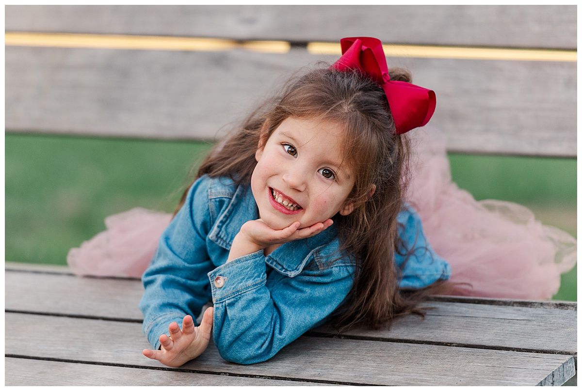Cute young girl poses for portrait in family photo session with dress bow jean jacket in Holliday Park Indianapolis
