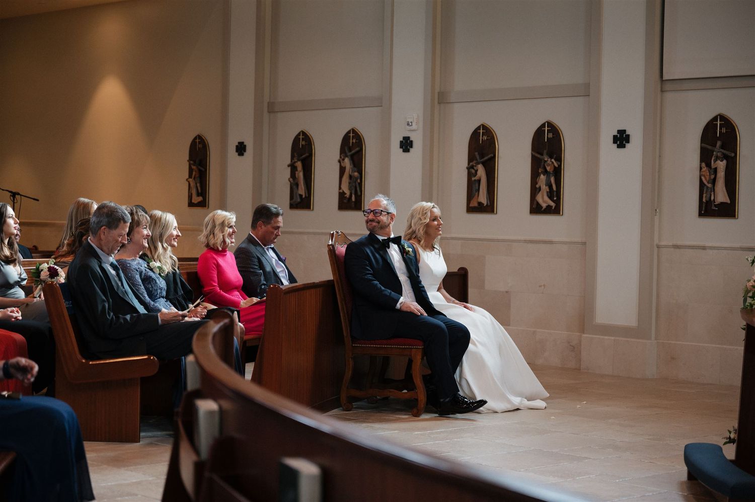 Wedding ceremony taking place in a traditional church sanctuary with wooden pews and decorative walls.