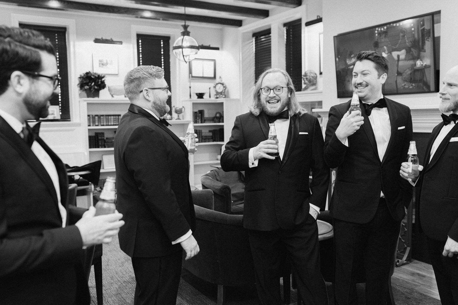Group of men in formal attire sharing drinks and conversation at an indoor gathering.