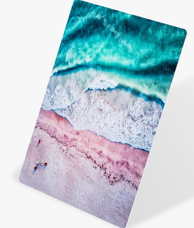 Aerial view of turquoise ocean waves meeting pink sandy beach.