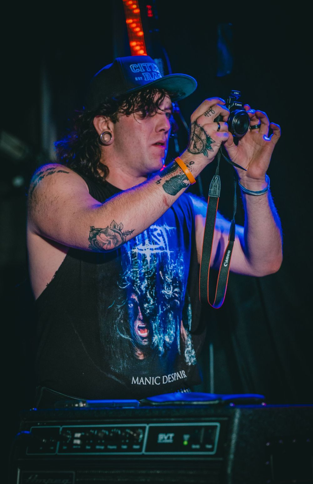 Concert photographer capturing shots during a live music performance in blue lighting.