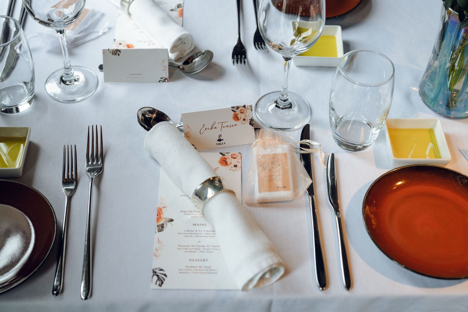Place settings with menus and orange charger plates arranged for an elegant wedding reception.