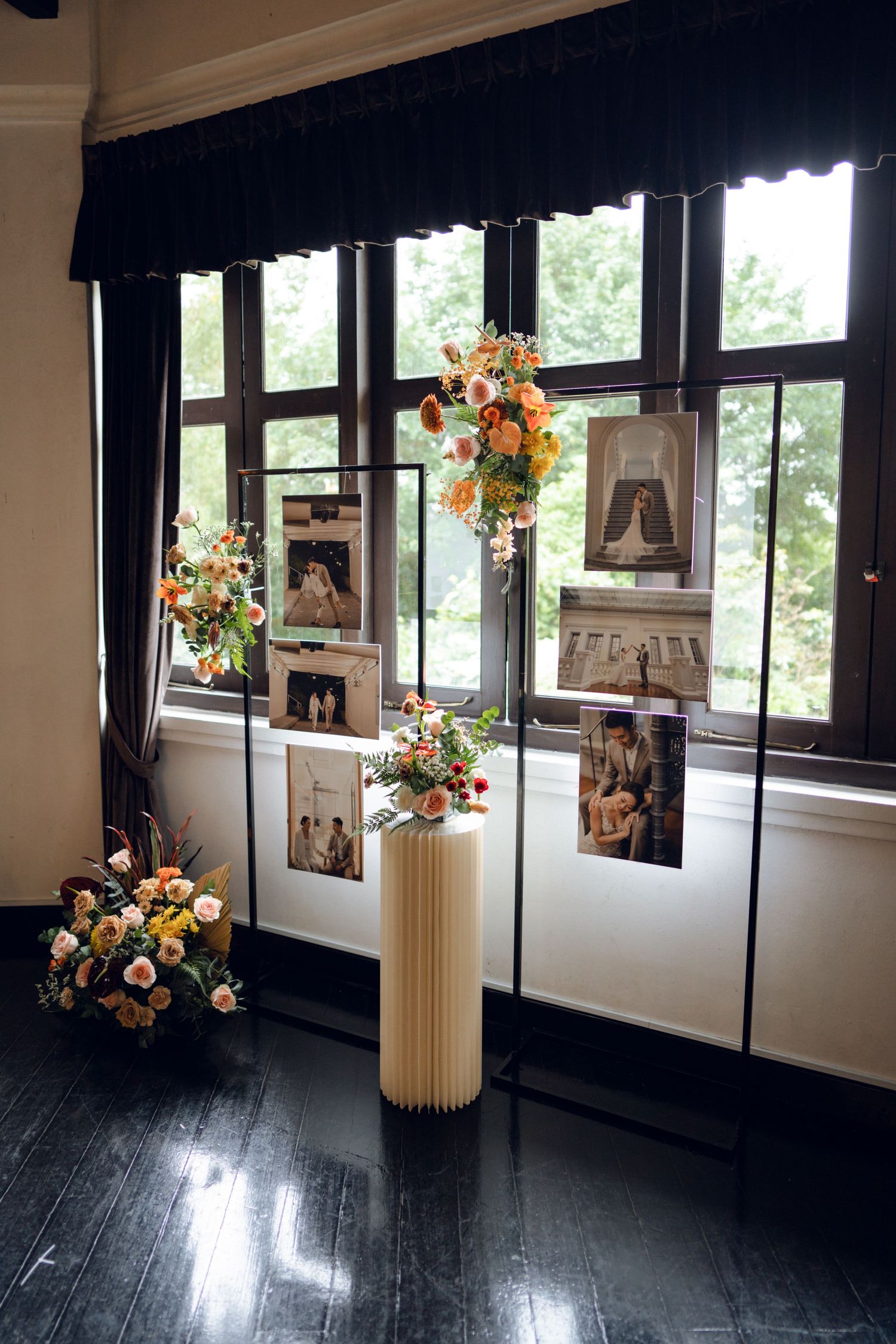 Elegant wedding venue interior with dark hardwood floors and floral arrangements in white vases near windows.