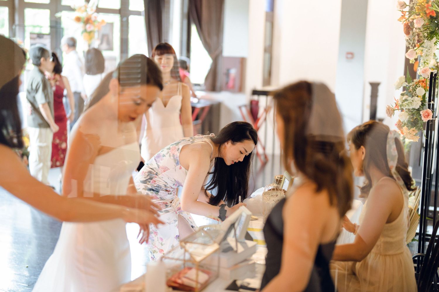 Celebration in an elegant white room with floral decorations and natural lighting.