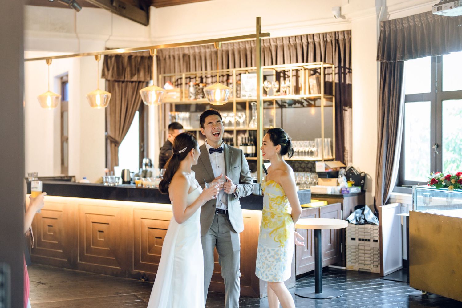 Modern reception venue with wood beams, curtains, and bar area.