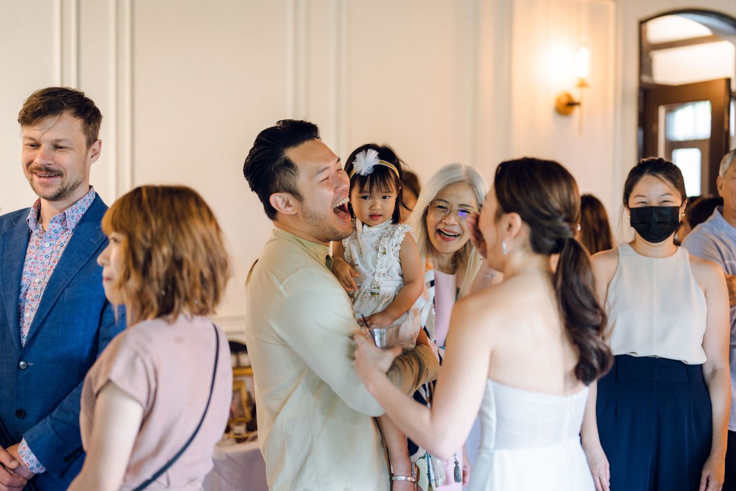 Wedding celebration with guests mingling in an elegant white room.