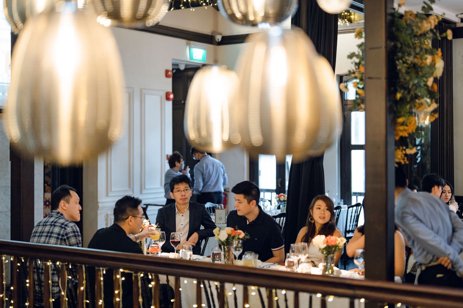 Elegant dining room with golden pendant lights and dark curtains creating an intimate atmosphere for guests.