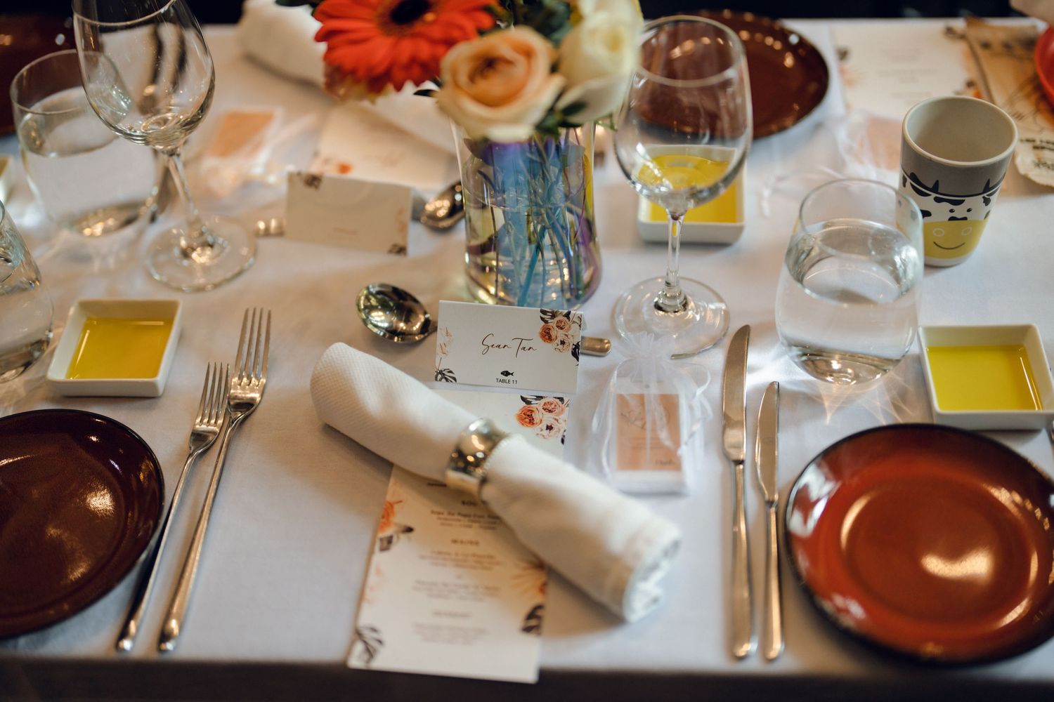 Elegant table settings with white linens, glassware, and menu cards at a formal event.